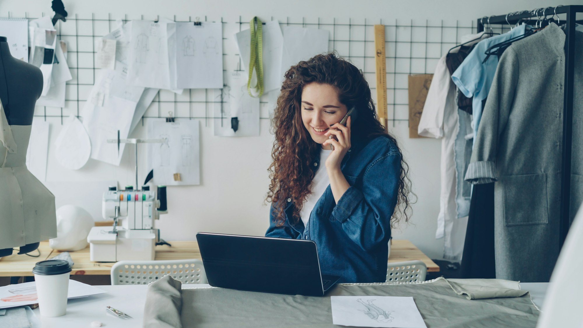 Ondernemer belt en werkt op haar laptop in haar atelier